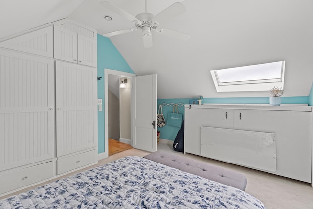 carpeted bedroom featuring vaulted ceiling with skylight, ceiling fan, and a closet