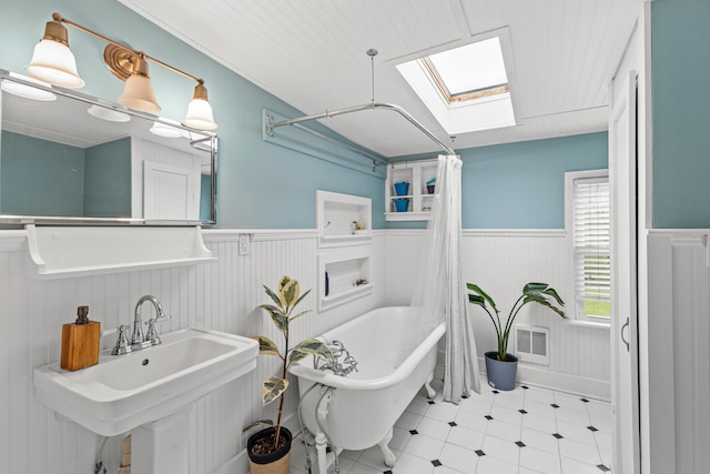 bathroom featuring a bath, a skylight, and sink