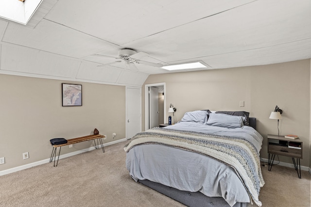 bedroom with vaulted ceiling with skylight, light carpet, and ceiling fan