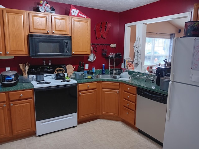 kitchen featuring electric stove, freestanding refrigerator, a sink, black microwave, and dishwasher