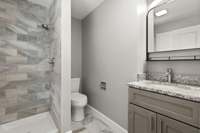 bathroom with tiled shower, vanity, and toilet