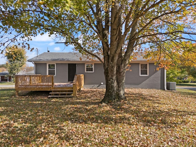 rear view of house with central air condition unit, a deck, and a lawn