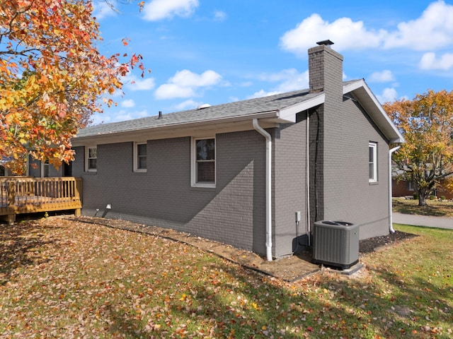 rear view of property with a lawn, cooling unit, and a wooden deck