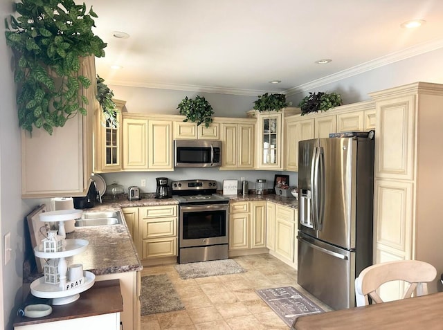 kitchen with cream cabinetry, ornamental molding, appliances with stainless steel finishes, and dark stone counters