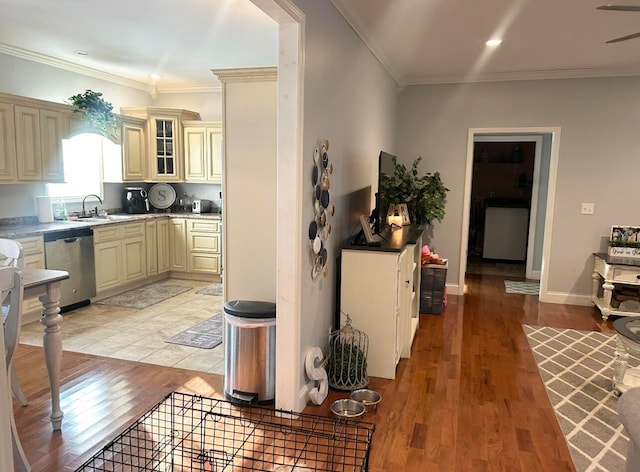 kitchen with crown molding, dishwasher, cream cabinets, and light hardwood / wood-style floors