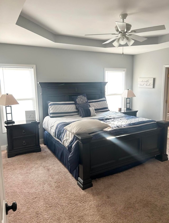 bedroom featuring ceiling fan, carpet floors, and a tray ceiling