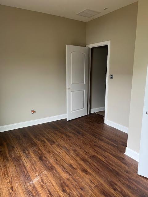 unfurnished room featuring dark wood-type flooring and baseboards