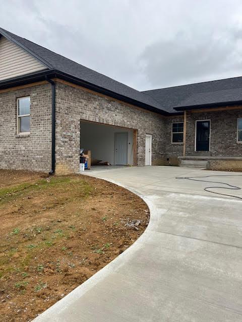 view of front of property with a garage, concrete driveway, and brick siding