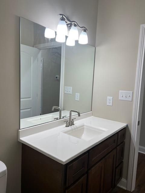 bathroom with toilet, baseboards, wood finished floors, and vanity