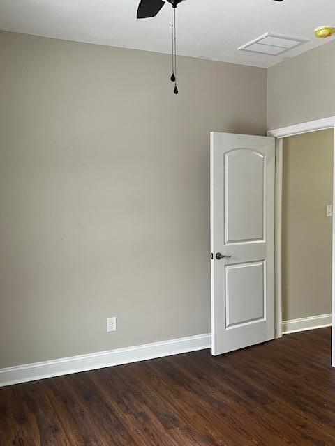 spare room featuring a ceiling fan, visible vents, dark wood finished floors, and baseboards