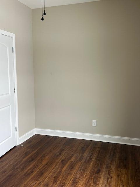 empty room featuring baseboards and dark wood finished floors