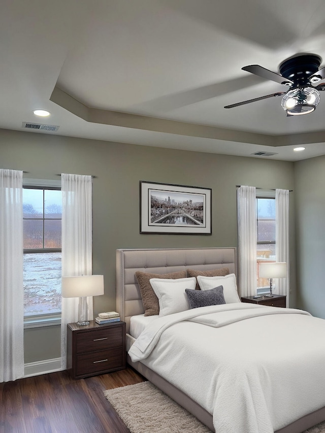 bedroom featuring a ceiling fan, dark wood-style flooring, visible vents, and baseboards