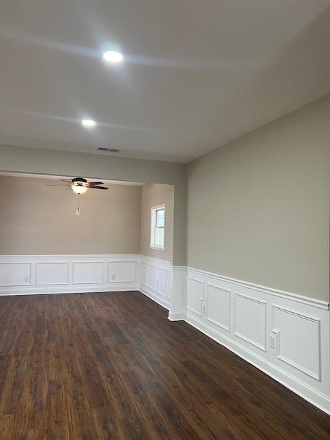 spare room with dark wood-style flooring, a wainscoted wall, recessed lighting, visible vents, and a ceiling fan