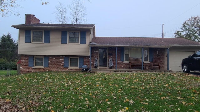 split level home with a porch, a garage, and a front yard