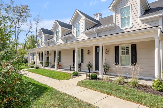 cape cod-style house with covered porch and a front yard