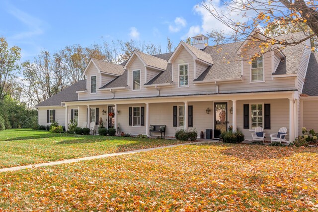 cape cod-style house featuring covered porch and a front yard