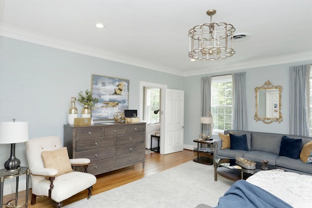 living room with an inviting chandelier, ornamental molding, and light hardwood / wood-style floors