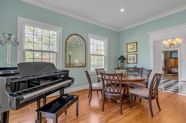 dining space with light hardwood / wood-style floors, crown molding, and an inviting chandelier