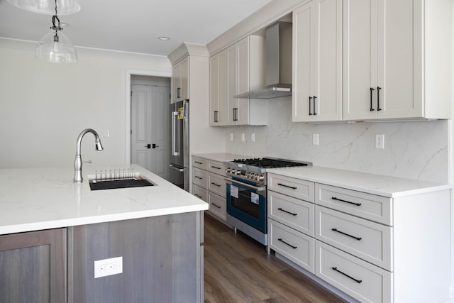 kitchen featuring light stone countertops, premium appliances, wall chimney exhaust hood, sink, and hanging light fixtures