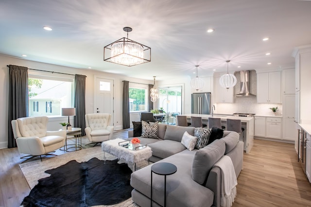 living room with a wealth of natural light, a chandelier, light hardwood / wood-style floors, and sink