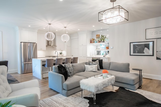 living room with light hardwood / wood-style floors, sink, and a notable chandelier