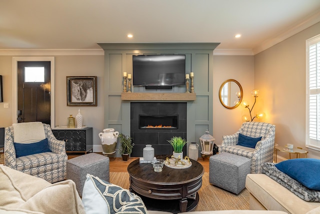 living room with a large fireplace, crown molding, and light hardwood / wood-style floors