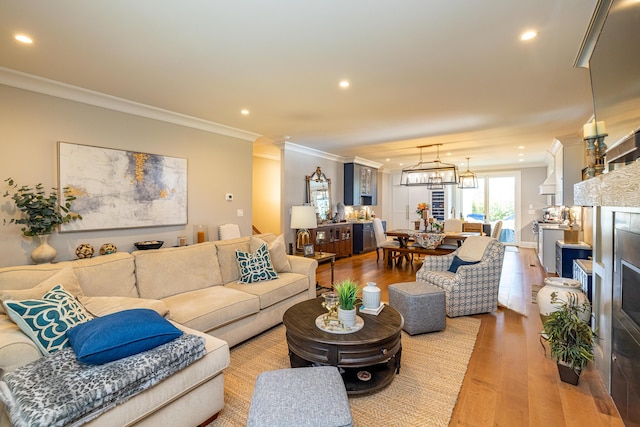 living room featuring wood-type flooring, ornamental molding, and a chandelier