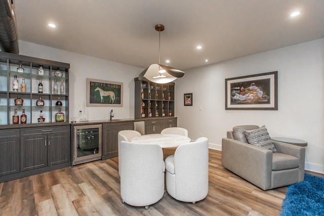 dining room with light wood-type flooring, indoor wet bar, and beverage cooler