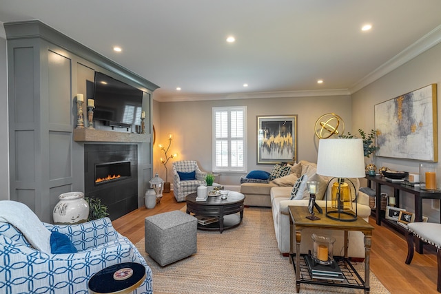 living room featuring ornamental molding, a fireplace, and light hardwood / wood-style flooring