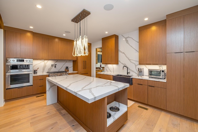 kitchen featuring backsplash, a spacious island, sink, hanging light fixtures, and stainless steel double oven