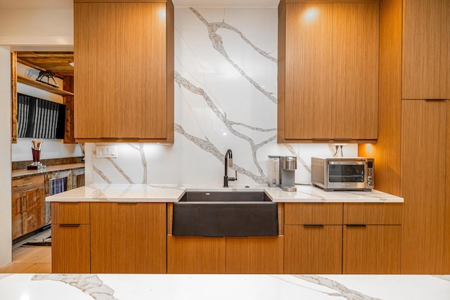 kitchen featuring light stone counters, sink, and decorative backsplash