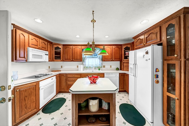 kitchen featuring pendant lighting, white appliances, sink, a textured ceiling, and a kitchen island