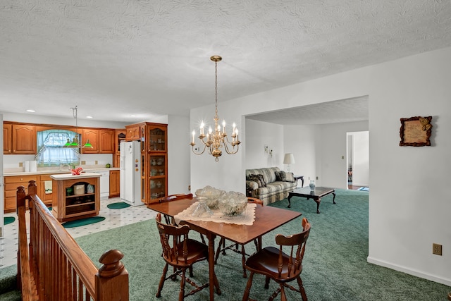 dining area with a textured ceiling, carpet floors, and an inviting chandelier