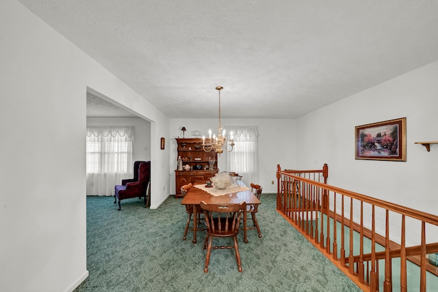 dining area featuring carpet, a chandelier, and a textured ceiling