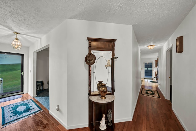 corridor with hardwood / wood-style floors and a textured ceiling