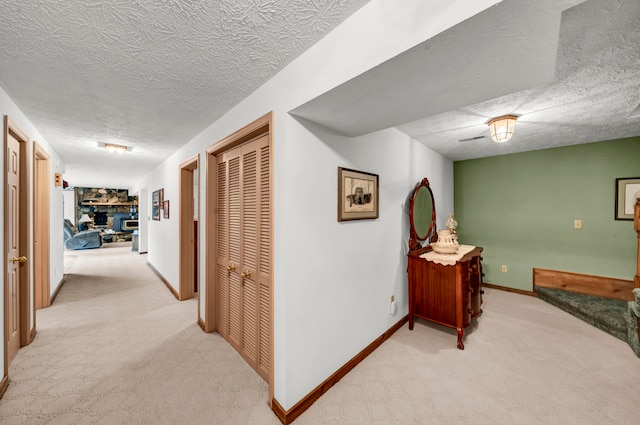 corridor with light carpet and a textured ceiling