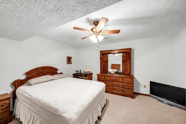 bedroom featuring ceiling fan, light colored carpet, and a textured ceiling