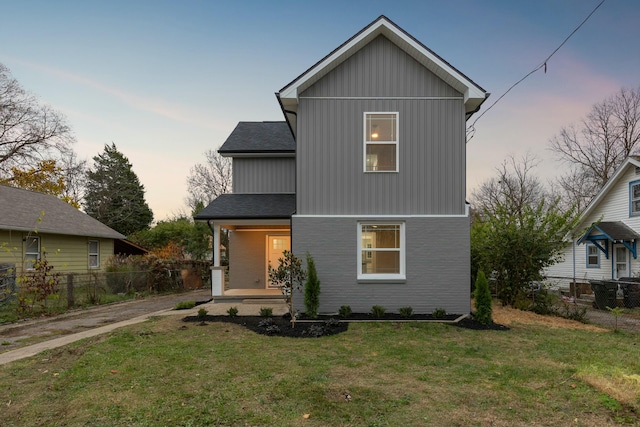 back house at dusk with a yard and covered porch