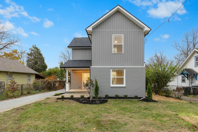 traditional-style home featuring a shingled roof, a porch, board and batten siding, a front yard, and fence