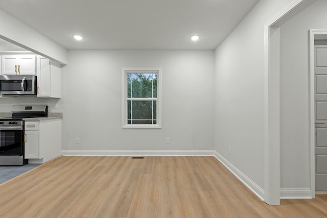 kitchen with light hardwood / wood-style flooring, white cabinets, and stainless steel appliances