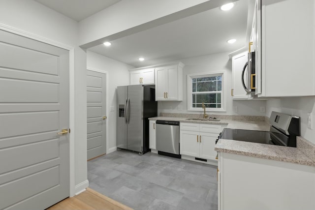 kitchen with light stone countertops, white cabinetry, sink, and stainless steel appliances