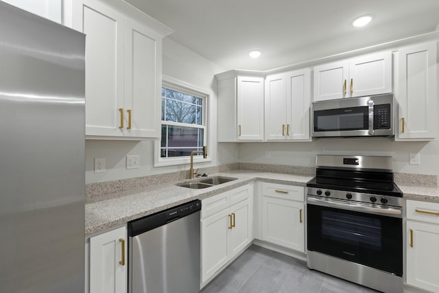 kitchen with light stone countertops, appliances with stainless steel finishes, white cabinetry, and sink