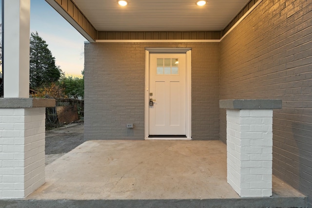 exterior entry at dusk with brick siding and a patio area