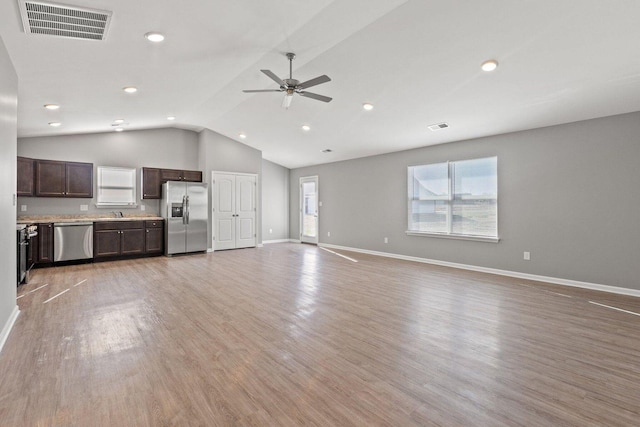 unfurnished living room with ceiling fan, a healthy amount of sunlight, vaulted ceiling, and light wood-type flooring