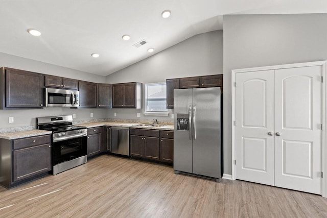 kitchen featuring lofted ceiling, sink, dark brown cabinets, light wood-type flooring, and stainless steel appliances