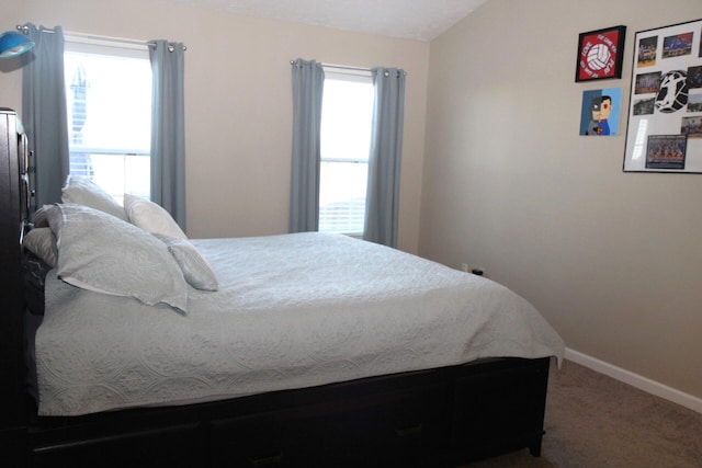 carpeted bedroom featuring vaulted ceiling and multiple windows