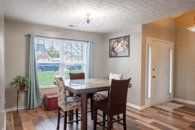 dining room featuring wood-type flooring, a textured ceiling, and a notable chandelier