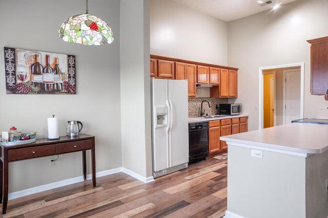 kitchen with dishwasher, a high ceiling, white refrigerator with ice dispenser, decorative light fixtures, and light wood-type flooring