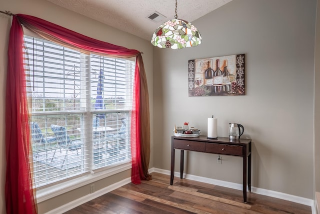 dining area with a textured ceiling, dark wood-type flooring, and a wealth of natural light