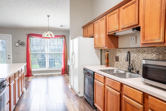 kitchen featuring pendant lighting, sink, hardwood / wood-style flooring, black dishwasher, and a textured ceiling